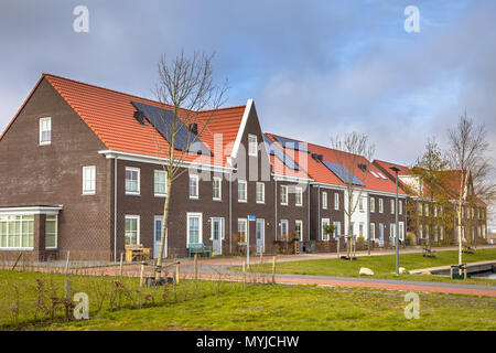 Moderne Reihenhäuser mit Solarzellen, braunen Backsteinen und roten Dachziegeln in Groningen Niederlande Stockfoto