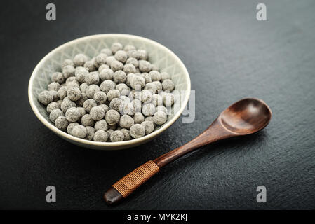 Raw Tapioka Perlen in der Platte auf schwarzem Schiefer Hintergrund. Für Bubble Tea Konzepte. Stockfoto