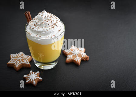 Weihnachten trinken Eierlikör in Glas mit Zimt und Cookies auf schwarzem Schiefer Hintergrund Stockfoto