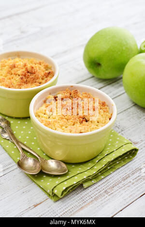 Apfel in kleine Auflaufform mit frischen Äpfeln auf hölzernen Hintergrund bröckeln Stockfoto