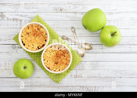 Apfel in kleine Auflaufform mit frischen Äpfeln auf hölzernen Hintergrund bröckeln Stockfoto