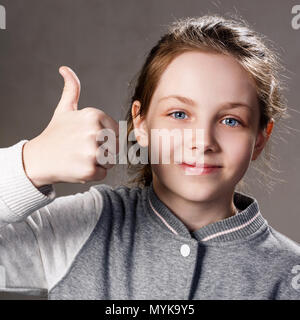 Schöne stets lächelndes Mädchen zeigt Daumen nach oben Geste. Stockfoto