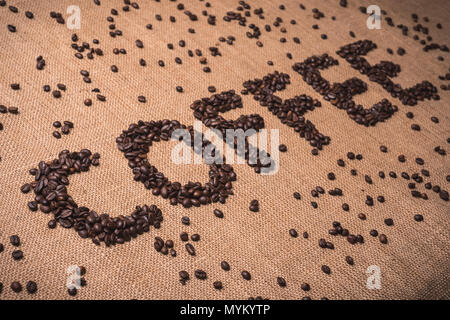 Kaffee Wort mit gerösteten Kaffeebohnen auf Draufsicht Zusammensetzung geschrieben Stockfoto