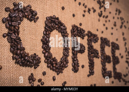 Kaffee Wort mit gerösteten Kaffeebohnen auf Draufsicht Zusammensetzung geschrieben Stockfoto