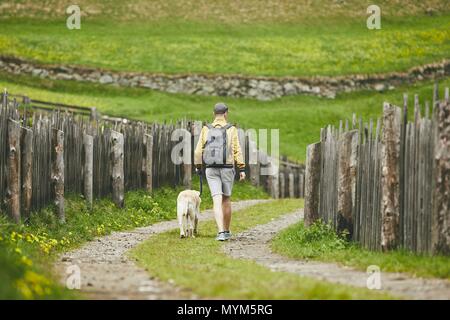 Tourist mit Hund in die Landschaft. Junge Menschen gehen mit Labrador Retriever auf Feldweg. Stockfoto