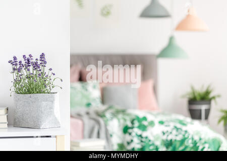 Lila Blüten in grau Material Pott gelegt auf dem Tisch stehend in hellen Innenraum Stockfoto