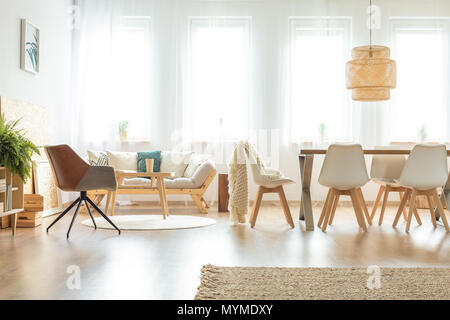 Vintage Sessel und das Sofa in der multifunktionalen Esszimmer mit hölzernen Tisch unter der Lampe Stockfoto