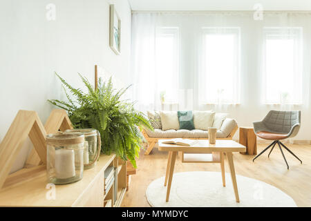 In der Nähe von Kerzen und fern auf einem Schrank im gemütlichen Wohnzimmer mit Holztisch auf weißen Teppich Stockfoto