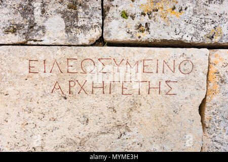 Antike griechische Inschrift auf einem alten Stein, die Teil einer Wand in einem historischen Gebäude in der Nähe zu sehen. Stockfoto