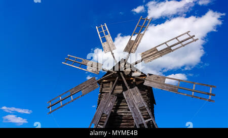 Niedrige Weitwinkelaufnahme eines alten und defekten Windmühle aus Holz gegen den blauen bewölkten Himmel als inspirierende Konzept für Bestrebungen und Utopie Stockfoto