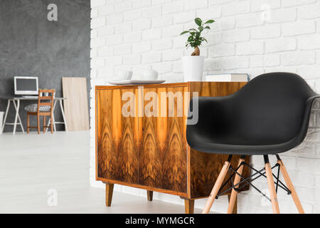 Helle Einrichtung mit alten, Holz kommode, schwarz Stuhl und Mauer Textur, home office im Hintergrund Stockfoto