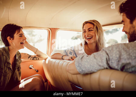 Gruppe von jungen Menschen und Frauen in einem Auto sitzen und Lachen. Junge Freunde durch ein Auto reisen und Spaß haben. Stockfoto