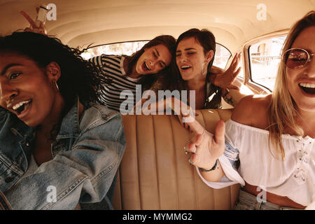 Junge weibliche Freunde auf einer Reise durch ein Auto, Reisen und eine tolle Zeit. Gruppe von Frauen, die mit dem Auto fahren. Stockfoto