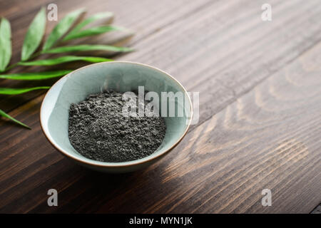 Schwarz kosmetische Ton in Coconut Schüssel auf Holz- Hintergrund closeup Stockfoto