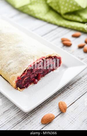 Cherry Strudel mit Mandeln und Puderzucker auf hölzernen Hintergrund Stockfoto