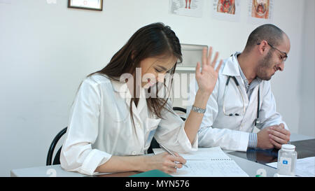 Junges Paar von Arzt und Krankenschwester lachend an jedem anderen nach einem Streit Stockfoto