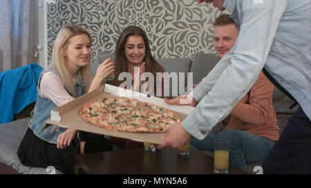 Gruppe von Freunden reden, wenn ihr Freund Pizza zum Mitnehmen holen Stockfoto