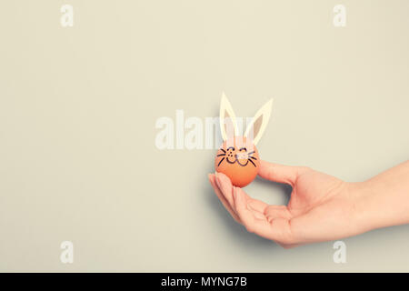 Eine Hand, die wenig Osterhase mit Papier Ohren, ab und Ei. Ostern Symbol. Stockfoto