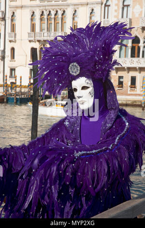 Campo della Salute, Dorsoduro Venedig, Italien: carnevale Nachtschwärmer tragen gefiederten Kostüm in Deep Purple, durch den Großen Kanal posing Stockfoto