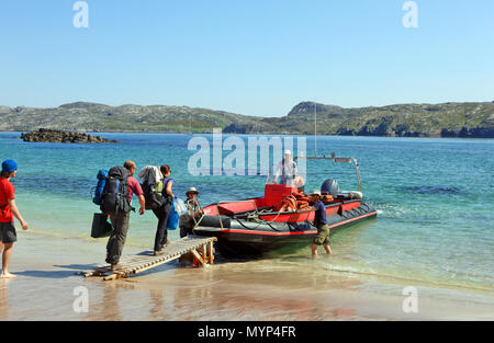 Scottish Wildlife Trust personal Holding mit der Fähre zum Festland, auf Handa Strand, während die Menschen verlassen die Insel mit der Rampe ihre Füße trocken zu halten. Stockfoto