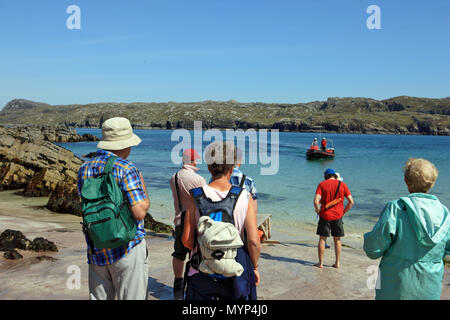 Besucher Handa Island, National Nature Reserve, Warten auf Tarbet auf die kleine Fähre nähert, landet auf dem Strand zurückzukehren. Stockfoto