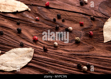 Mehrfarbige Korn Pfeffer und Lorbeer auf hölzernen Hintergrund close-up Stockfoto