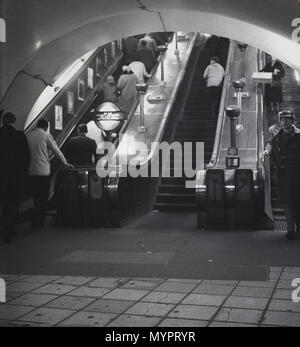 1960er, historisches Bild aus dieser Zeit, in der Menschen die hölzernen Rolltreppen der Londoner U-Bahn, der Metro oder des öffentlichen Nahverkehrs nach London, England, fahren. Stockfoto