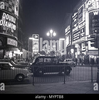 1960er, historisch, nachts und ein traditionelles schwarzes londoner Taxi am Piccadilly Circus, mit den berühmten Neonlichtern und Werbetafeln, die die Gegend beleuchten. Stockfoto