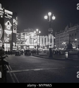1960s, von der Regent Street aus gesehen, sehen wir Piccadilly Circus bei Nacht, london, england, mit den beleuchteten Neonwerbewänden.die Kreuzung und der öffentliche Raum wurden 1819 gebaut, um Piccadilly mit der Regent Street zu verbinden und ist ein wichtiges Touristenziel im West End der Stadt. Stockfoto