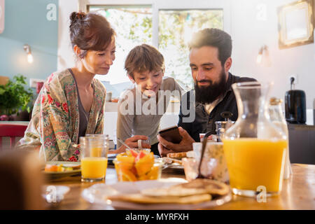 Family Mit Frühstück, Papa Aktien ein Video auf einem Telefon zu seinem Sohn Stockfoto
