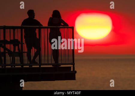 Aberystwyth Wales UK, Donnerstag, 07. Juni 2018 Deutschland Wetter: Der sehr heißen, sonnigen Sommer Sonnenschein weiter, wobei der Tag endet in einem herrlichen Sonnenuntergang über Leute pn am Meer Pier in Aberystwyth auf der Cardigan Bay Küste von West Wales Foto © Keith Morris/Alamy leben Nachrichten Stockfoto