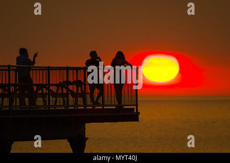 Aberystwyth Wales UK, Donnerstag, 07. Juni 2018 Deutschland Wetter: Der sehr heißen, sonnigen Sommer Sonnenschein weiter, wobei der Tag endet in einem herrlichen Sonnenuntergang über Leute pn am Meer Pier in Aberystwyth auf der Cardigan Bay Küste von West Wales Foto © Keith Morris/Alamy leben Nachrichten Stockfoto