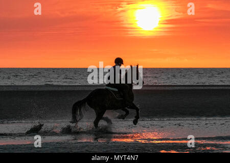 Reiten in den Sonnenuntergang, Southport, Merseyside. 7. Juni 2018. Nach einem fantastischen Sommer, 15 Jahre alte Paul galoppiert sein Pferd, 9 Jahre alte Stute 'Jessie', durch den zurückweichenden Tidal Waters als atemberaubende Sonnenuntergang schmiegt sich in den Horizont über den Badeort Southport in Merseyside. Credit: cernan Elias/Alamy leben Nachrichten Stockfoto