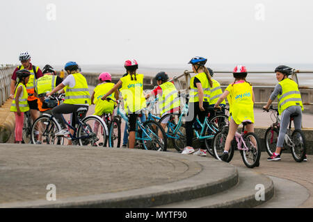 Sky Ride geführte Fahrten und Fahrradschulungen in Blackpool, Großbritannien. Diese Gruppen von Kindern tragen reflektierende Kleidung Kinderlehrer, oft etwa 20 Personen, fahren mit einem British Cycling Ride Leader, einem gut ausgebildeten und erfahrenen Fahrer, der die Kinder auf einer speziell ausgewählten Route führt, oft im Gelände, um Selbstvertrauen und Spaß auf dem Fahrrad zu schaffen. Stockfoto