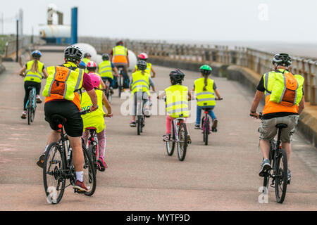 Sky Ride geführte Fahrten und Fahrradschulungen in Blackpool, Großbritannien. Diese Gruppen von Kindern tragen reflektierende Kleidung Kinderlehrer, oft etwa 20 Personen, fahren mit einem British Cycling Ride Leader, einem gut ausgebildeten und erfahrenen Fahrer, der die Kinder auf einer speziell ausgewählten Route führt, oft im Gelände, um Selbstvertrauen und Spaß auf dem Fahrrad zu schaffen. Stockfoto