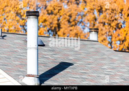 Nahaufnahme von Haus Schindeln auf dem Dach Dach mit Kamin, Herbst orange gelb golden Blatt Blätter am Baum im Hintergrund Stockfoto