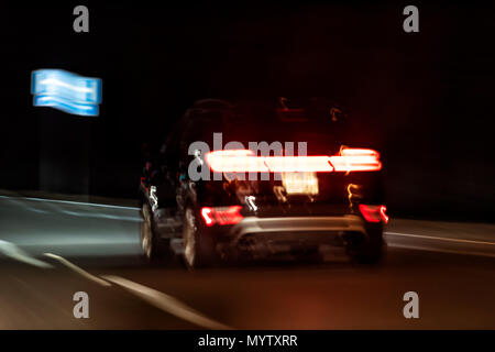 Abstrakte Nahaufnahme eines Autos in dunkler Nacht Abend bunte Farben, Straßenlaternen, rot Bremsen Form Stockfoto