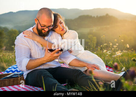 Paar sitzt auf einer Picknickdecke mit Weingläsern außerhalb Stockfoto