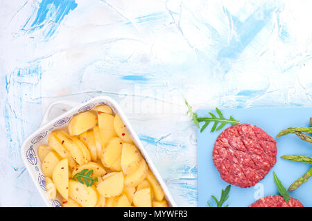 Rohe Koteletts aus Rindfleisch für Grill und Kartoffeln. Fleisch für das Kochen Mittagessen und Gewürze und Spargel. Hintergrund für Text. Flach Stockfoto