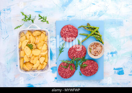 Rohe Koteletts aus Rindfleisch für Grill und Kartoffeln. Fleisch für das Kochen Mittagessen und Gewürze und Spargel. Fitness Nahrung. Hintergrund für Text. Flach Stockfoto