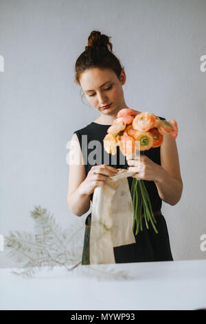 Florist arrangieren ein Bouquet von orange-gelben Ranunculus asiaticus Stockfoto