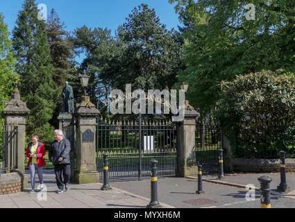 Leute an den Toren zu den Botanischen Gärten in Belfast mit einer Statue von Kelvin im Hintergrund. Stockfoto