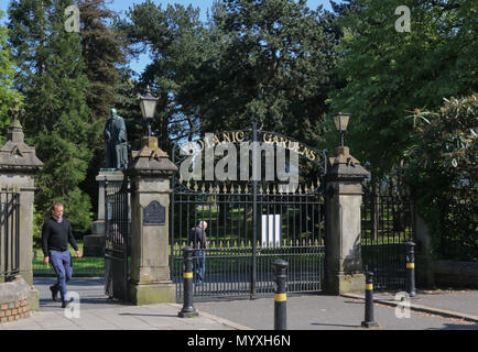 Leute an den Toren zu den Botanischen Gärten in Belfast mit einer Statue von Lord Kelvin im Hintergrund. Stockfoto