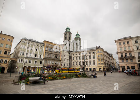 Ein Zug geht durch den Hauptplatz (Hauptplatz) der Altstadt von Linz, Österreich. Die Alter Dom (Kathedrale) ist im Hintergrund. Stockfoto