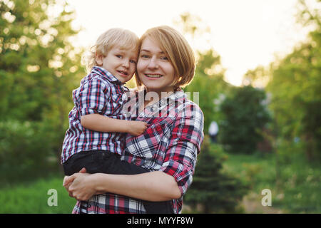 Mutter und Sohn in karierten Hemden. Frau und junge, starke umfasst. Zeit mit der Familie zusammen. Stockfoto