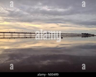 Großbritannien Wetter 25. Oktober. Cloud und dunstigen Herbstsonne in Southport. Southport Pier spiegelt sich im Wasser am Strand bei Ebbe. Stockfoto