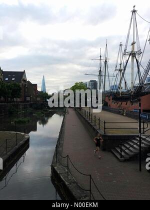 London, UK. 28. Mai 2017. Grauen Himmel ist hinter den Shard London gesehen, wie ein Jogger vorbei das Tobacco Dock Piratenschiff in Ost-London heute Abend bei mild aber feucht Wetter läuft. Bildnachweis: Vickie Flores/StockimoNews/Alamy Live-Nachrichten Stockfoto