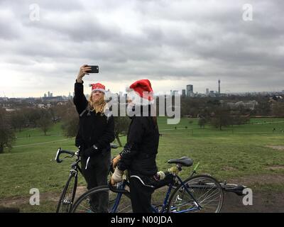 London, Großbritannien. 25 Dez, 2017. Zwei Radfahrer in Santa Hüte feiern Weihnachten auf der Primrose Hill in London am 25. Dezember 2017 Quelle: rosenthal Jon/StockimoNews/Alamy leben Nachrichten Stockfoto