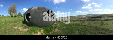 UK Wetter: Sonnig in Wycoller, Lancashire. Schönen sonnigen Tag am Atom Panoptikum mit Blick auf Wycoller als junges Mädchen entspannt in der Skulptur Stockfoto