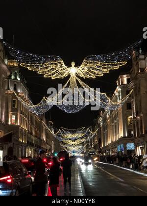 Käufer bewundern die Weihnachtsbeleuchtung und trotzen dem Regen in der Regent Street in London am 23. Dezember 2018 Stockfoto